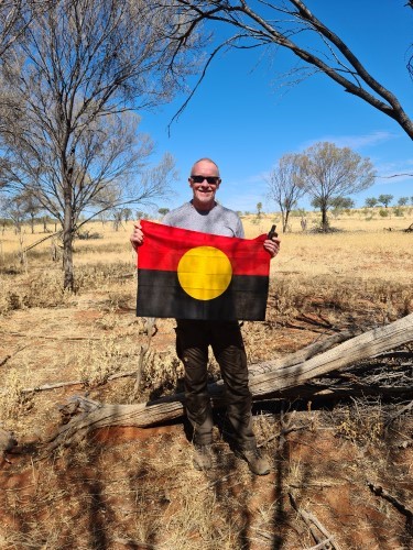Chris stood with Aboriginal Flag at the pole